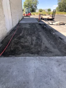 Freshly removed section of concrete alongside a commercial building in Eastern Idaho, with gravel base prepped for repour or utility access